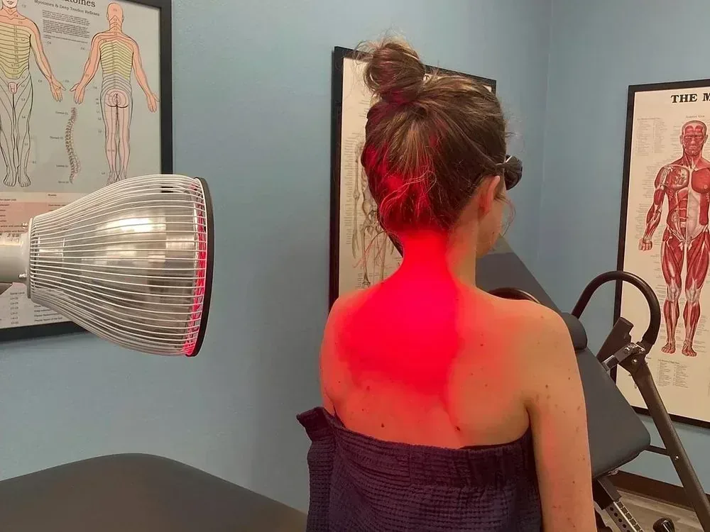 Infrared therapy lamp positioned over a patient’s shoulders and upper back