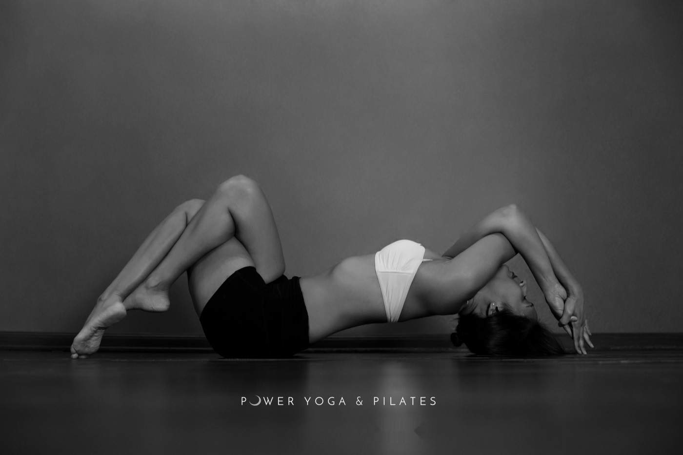 A deep floor backbend, black and white studio portrait