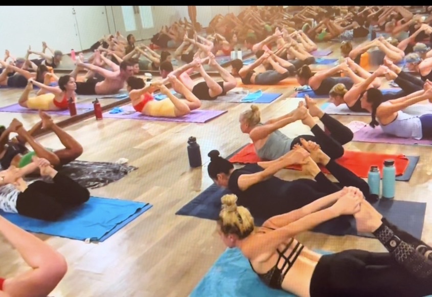 A full class holding bow pose at the Sahara flagship