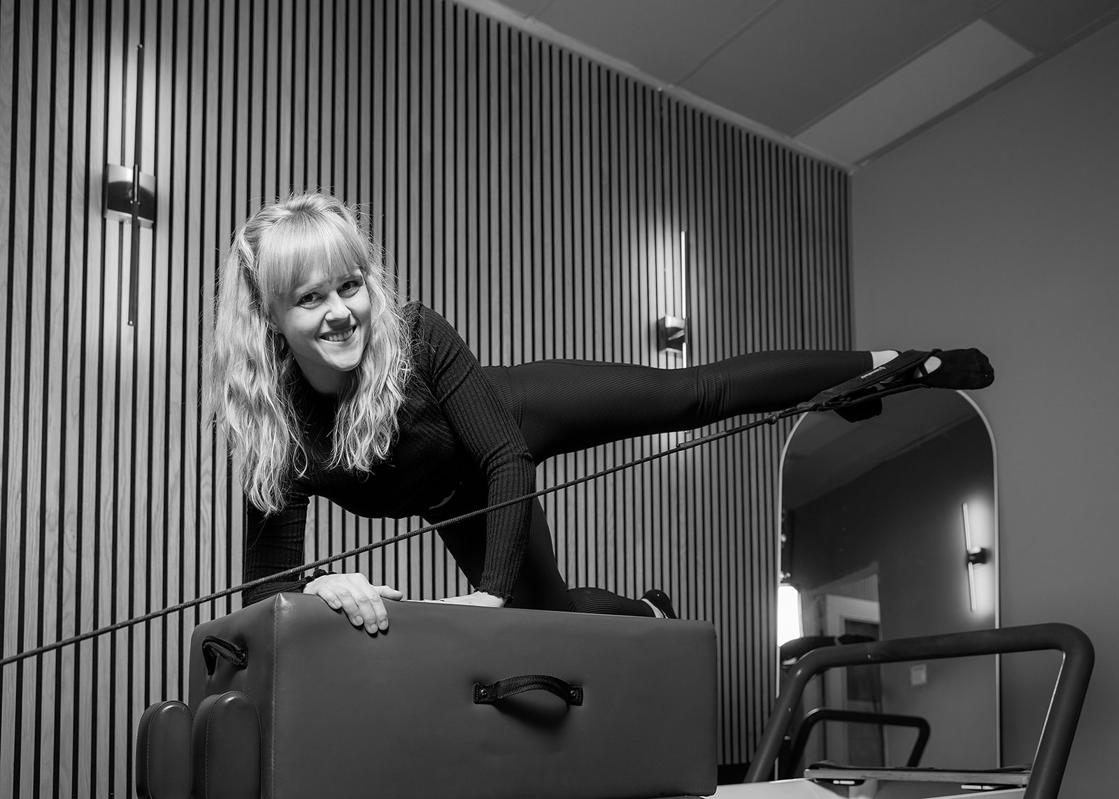 A teacher demonstrating a supported leg extension on the apparatus at Power Yoga + Pilates + Fitness