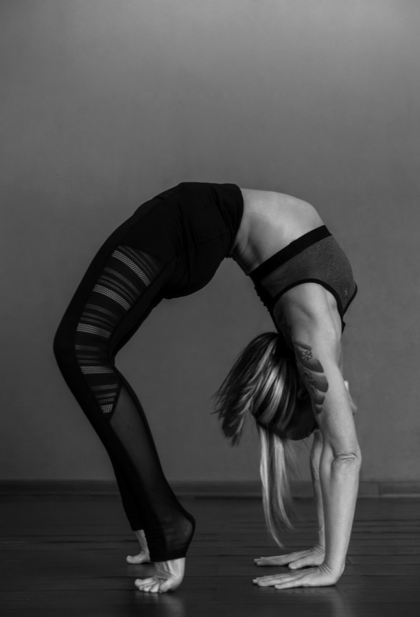 An instructor holding a standing wheel backbend